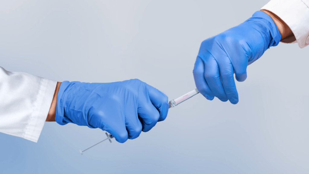 Hands with medical gloves capping a syringe